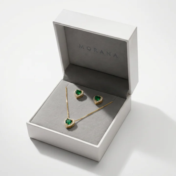 Conjunto de colar e brincos Morana com pedras verdes em formato de coração, apresentado em caixa de presente da marca.